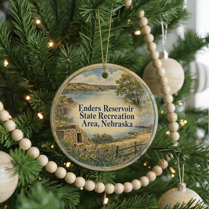 A round ornament hanging on a Christmas tree, featuring a scenic landscape of the Enders Reservoir State Recreation Area in Nebraska.