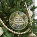 A round ornament hanging on a Christmas tree, featuring a scenic image of Eno River State Park in North Carolina.