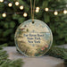 A round ornament with a lighthouse and beach scene, surrounded by greenery and a string of lights.