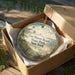 A decorative ornament in a wooden box, featuring a lighthouse and a beach scene, with the text "Fair Haven Beach State Park, New York" on it.