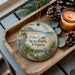 A decorative ornament featuring a scenic landscape of Cape State Park, Virginia, with pine cones and a lit candle on a wooden tray.