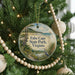 A Christmas tree decorated with ornaments, including a circular ornament with a scenic image of False Cape State Park, Virginia.