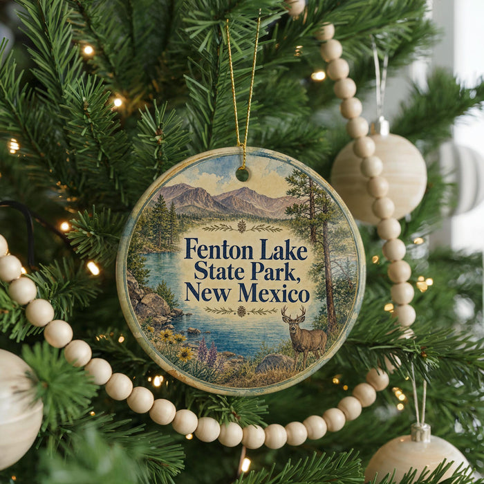 A round ornament hanging on a Christmas tree, featuring a scenic image of Fenton Lake State Park, New Mexico.