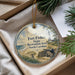 A round ornament with a lighthouse and beach scene, hanging from a string.