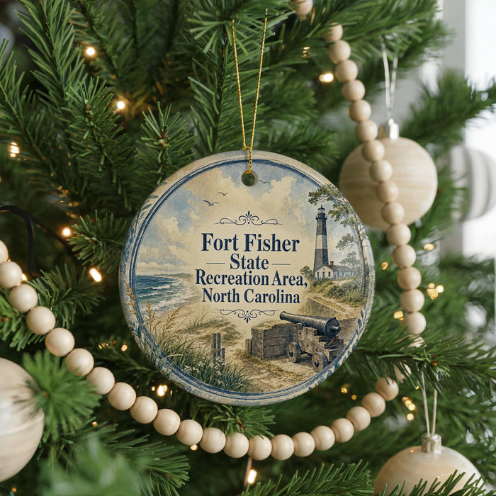 A round ornament hanging on a Christmas tree, featuring a lighthouse and a coastal scene.