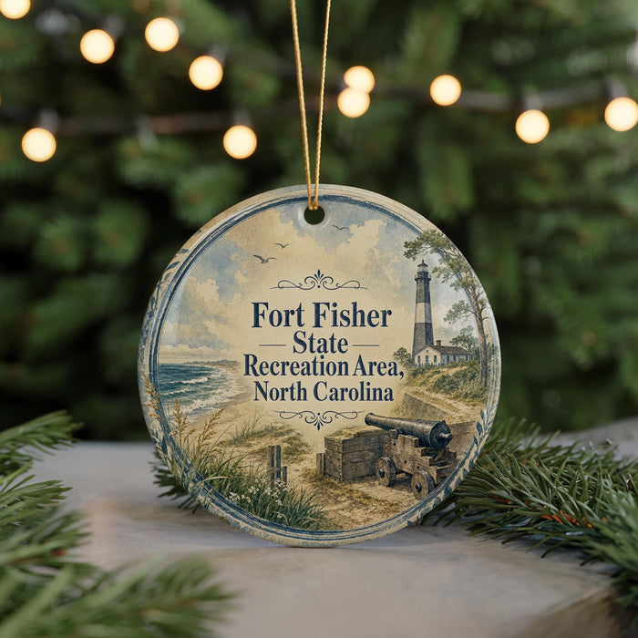 A round ornament with a lighthouse and beach scene, featuring text that reads "Fort Fisher State Recreation Area North Carolina".