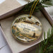 A decorative ornament in a box, featuring an illustration of Fort Leaton, a historic site in Texas.