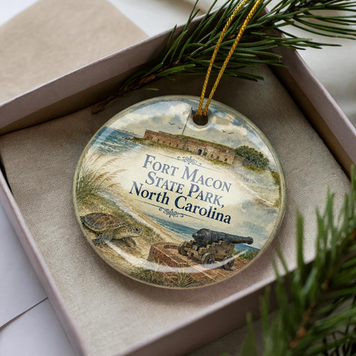 A decorative ornament in a box, featuring an illustration of Fort Mason State Park in North Carolina.
