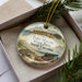 A decorative ornament in a box, featuring an illustration of Fort Mason State Park in North Carolina.