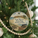 A round ornament hanging on a Christmas tree, featuring a picture of Fort Macon State Park in North Carolina.