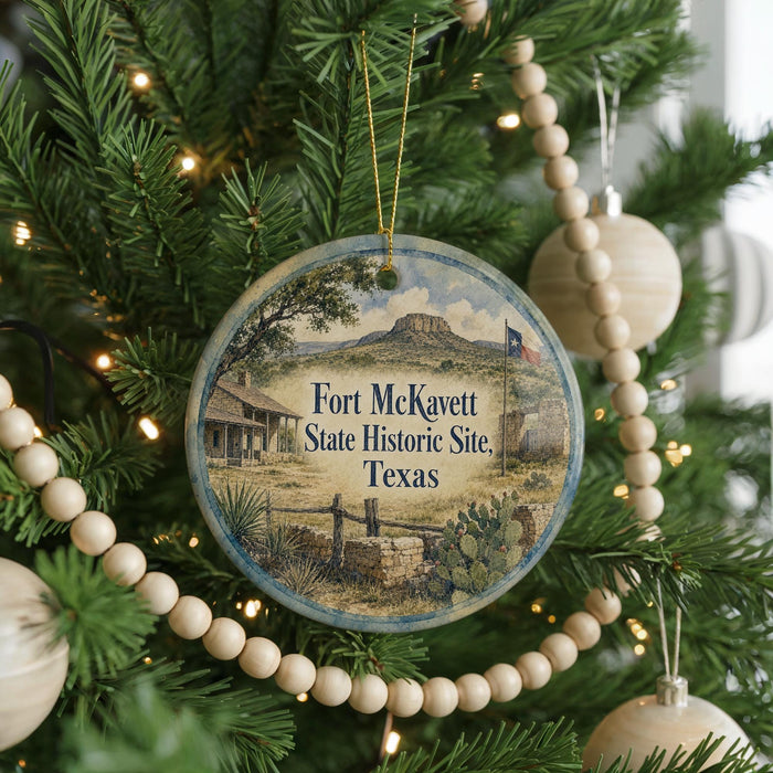 A round ornament hanging on a Christmas tree, featuring a scenic image of Fort McKinett, Texas.