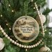 A round ornament hanging on a Christmas tree, featuring a scenic image of Fort Owen State Park in Montana.
