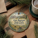 A round ornament with a scenic illustration of Fort Ransom State Park in North Dakota, featuring a house, a river, and wildlife.