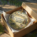 A decorative ornament in a wooden box, featuring an illustration of Fort Robinson State Park in Nebraska.