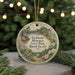 A round ornament with a scenic landscape and a bird, hanging on a string.