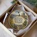 A decorative ornament in a box, featuring a scenic landscape with a dome-shaped building, flowers, and a path leading to a body of water.