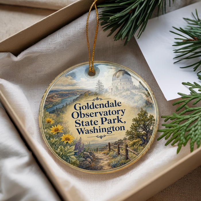 A decorative ornament with a scenic landscape featuring a domed building, trees, and a path, hanging from a string.