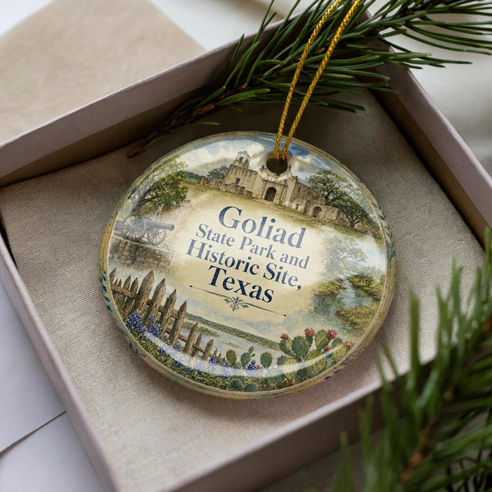 A decorative ornament in a box, featuring a scenic image of the Goliad State Park and Historic Site in Texas.