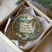A round ornament with a scenic landscape of Gorges State Park, North Carolina, featuring a waterfall and a bird perched on a branch.