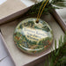 A decorative ornament in a box, featuring a scenic landscape of the Governor Knows State Forest in Wisconsin.