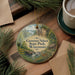 A decorative ornament featuring a scenic landscape of Governor Nelson State Park in Wisconsin, with pine branches and a cup of coffee nearby.