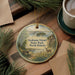 A decorative ornament featuring a scenic landscape of Grahams Island State Park in North Dakota, with a bench, pine trees, and a deer in the foreground.