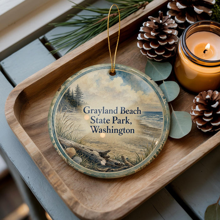 A wooden tray with a decorative ornament featuring a scenic beach landscape, pine cones, and a lit candle.