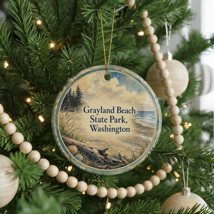 A round ornament hanging on a Christmas tree, featuring a scenic image of a beach and a pine tree.
