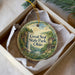 A decorative ornament in a box, featuring a scenic landscape with a waterfall and a house, with the text "Great Seal State Park, Ohio" printed on it.