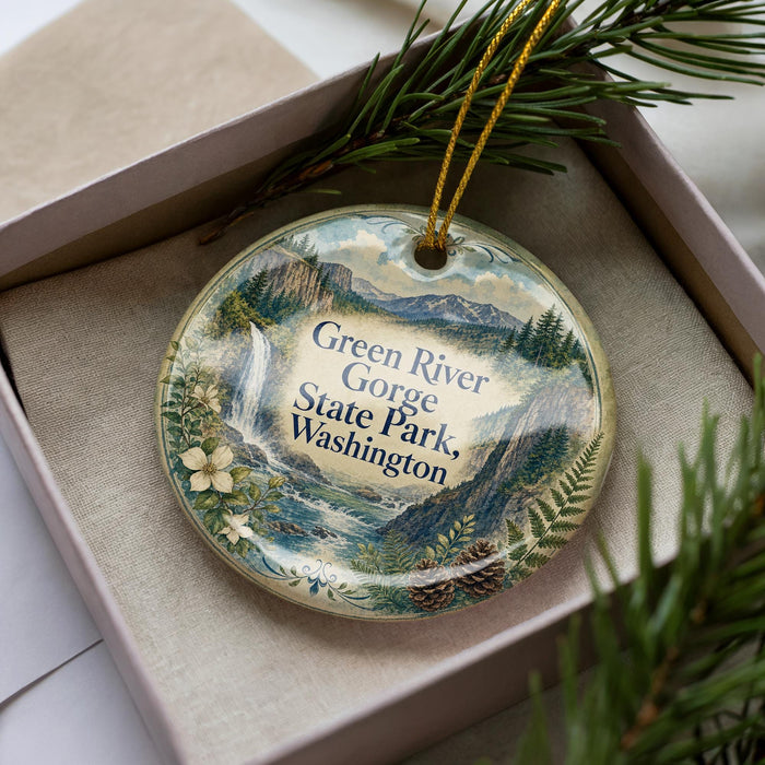 A decorative ornament with a scenic landscape of the Green River Gorge State Park in Washington, featuring mountains, waterfalls, and pine trees.