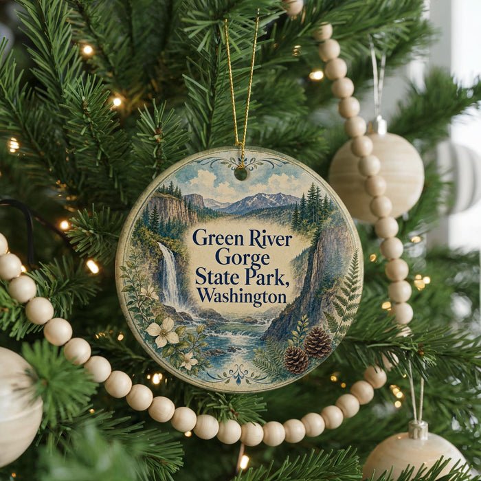 A round ornament hanging on a Christmas tree, featuring a scenic image of the Green River Gorge State Park in Washington.