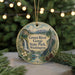 A circular ornament with a scenic landscape of a waterfall, mountains, and pine trees, surrounded by greenery and a string of lights.