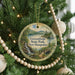 A Christmas tree decorated with ornaments, including a circular ornament with a scenic landscape of a waterfall and forest.
