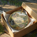 A decorative ornament in a wooden box, featuring a scenic image of the Greenwood Furnace State Park in Pennsylvania.