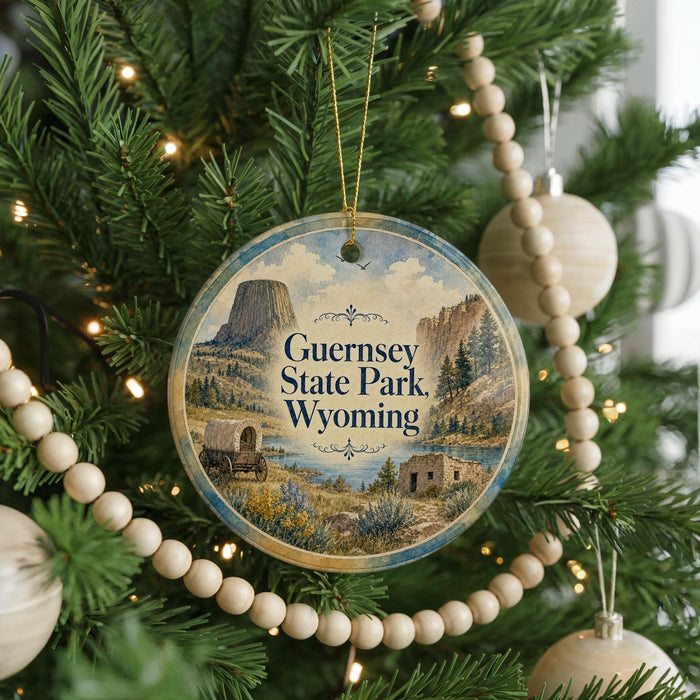 A round ornament hanging on a Christmas tree, featuring a scenic image of Guernsey State Park, Wyoming.