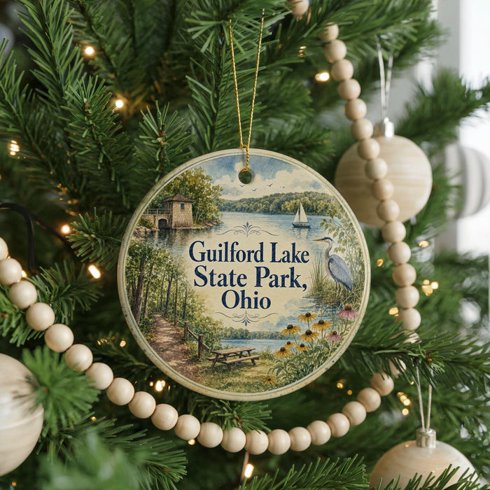 A round ornament hanging on a Christmas tree, featuring a scenic image of Guilford Lake State Park, Ohio.