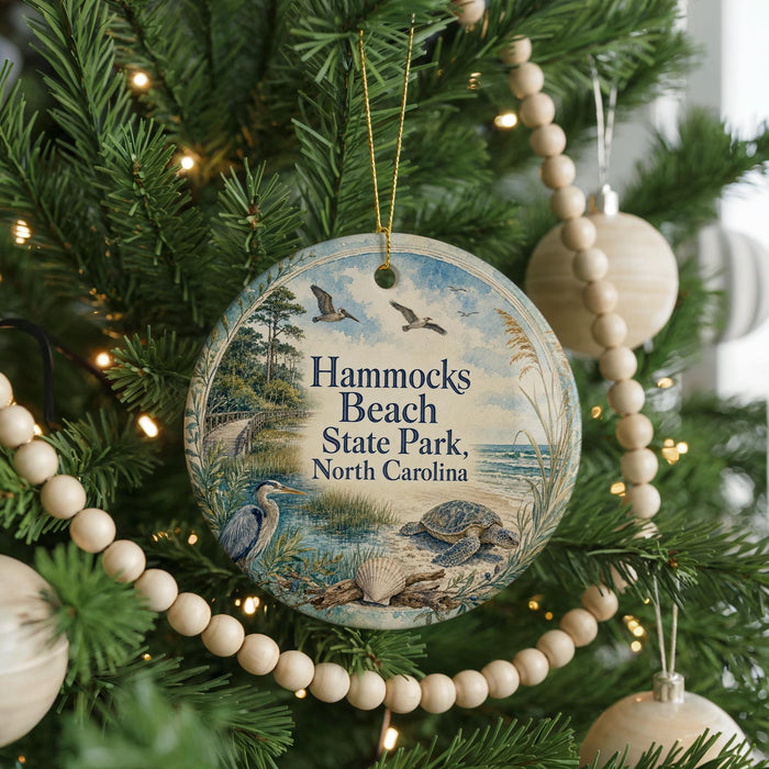 A round ornament hanging on a Christmas tree, featuring a beach scene with birds and a turtle.