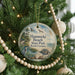 A round ornament hanging on a Christmas tree, featuring a beach scene with birds and a turtle.