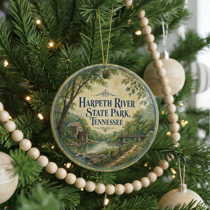 A round ornament hanging on a Christmas tree, featuring a scenic image of Harpeth River State Park, Tennessee.