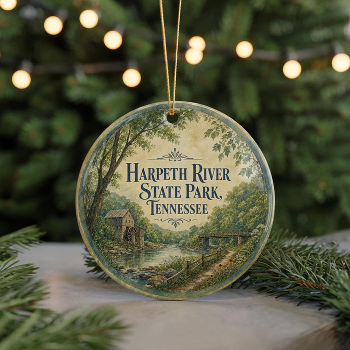 A round ornament with a scenic image of Harpeth River State Park in Tennessee, featuring a mill and a bridge, surrounded by greenery and a string of lights.