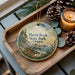 A decorative ornament featuring a scenic landscape of Harris Beach State Park, Oregon, with pine cones and a lit candle on a wooden tray.