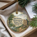 A round ornament with a scenic landscape of a river, mountains, and trees, hanging from a string.