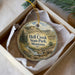 A decorative ornament in a box, featuring a scenic landscape with mountains, trees, and a dinosaur.
