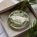 A decorative ornament with a scenic landscape of Henry Horton State Park, Tennessee, displayed in a box with pine branches.