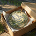 A decorative ornament in a box, featuring a scenic image of the High Bridge Trail in Virginia.