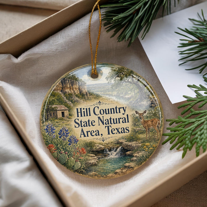 A decorative ornament with a scenic landscape featuring a river, mountains, and a deer, along with the text "Hill Country State Natural Area, Texas".