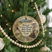 A round ornament hanging on a Christmas tree, featuring an illustration of a train and a scenic landscape.