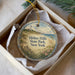 A decorative ornament in a box, featuring a lighthouse and a beach scene, with the text "Hither Hills State Park, New York" printed on it.