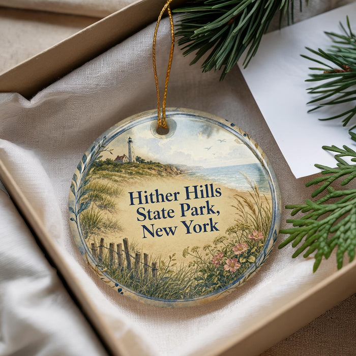 A decorative ornament with a lighthouse and beach scene, placed in a box with pine branches.