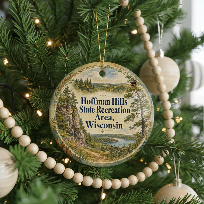 A round ornament hanging on a Christmas tree, featuring a scenic landscape with a river and mountains.